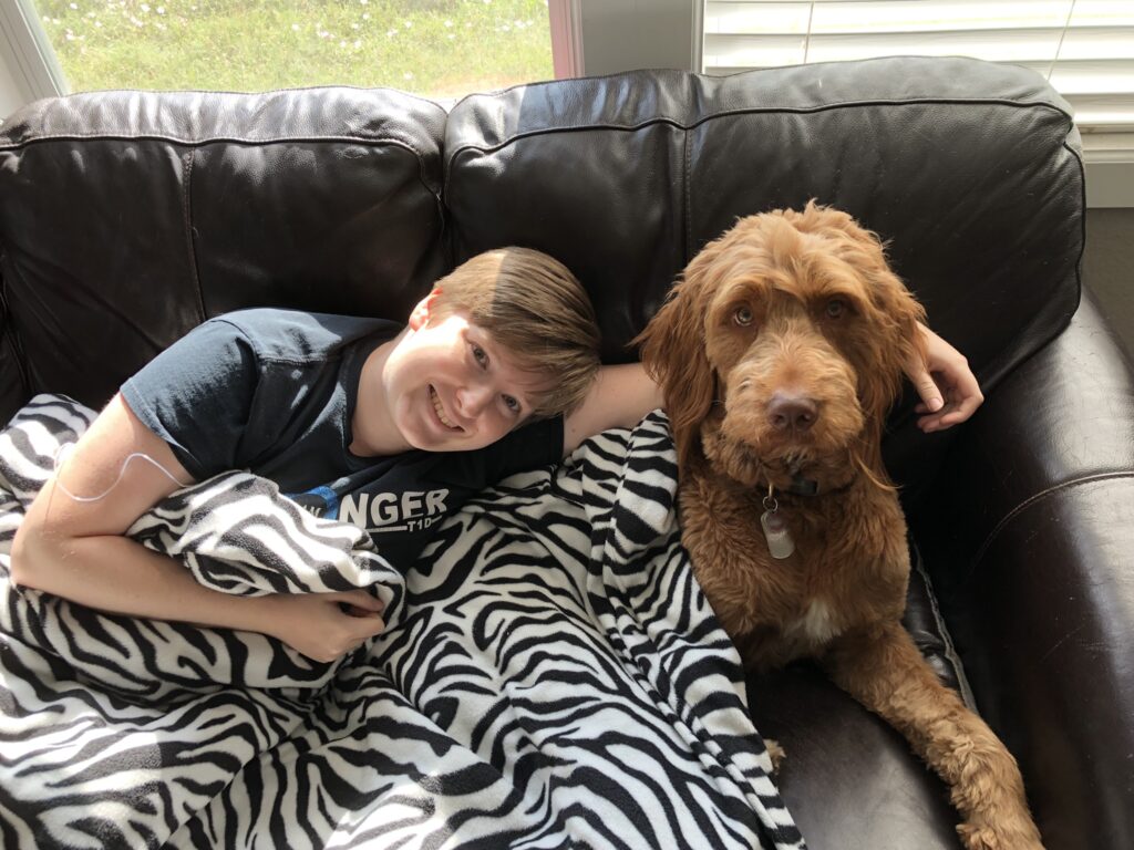 Clara and Arlo cuddling on the couch under a zebra pattern blanket.